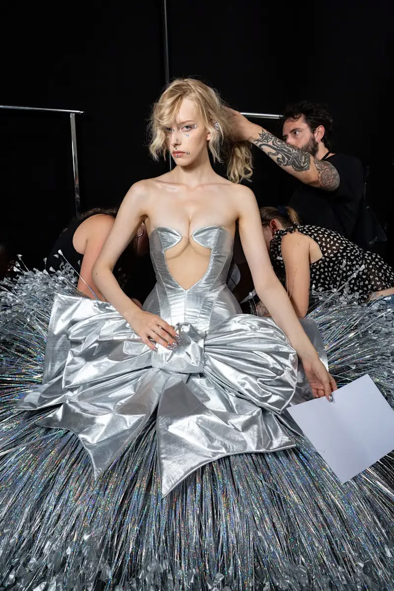 Model in silver gown, stylists at work